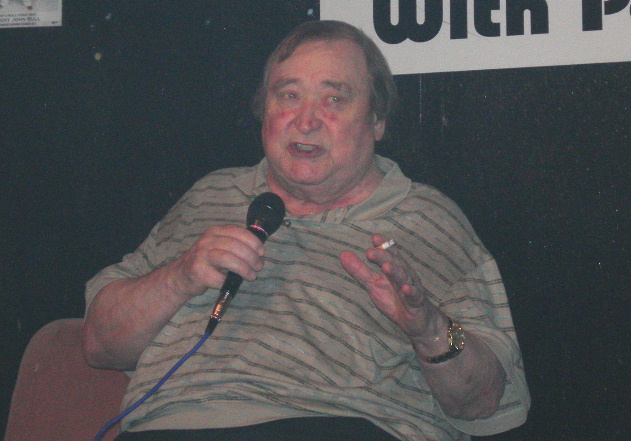 Stand up comedian Bernard Manning seated with a lighted cigarette